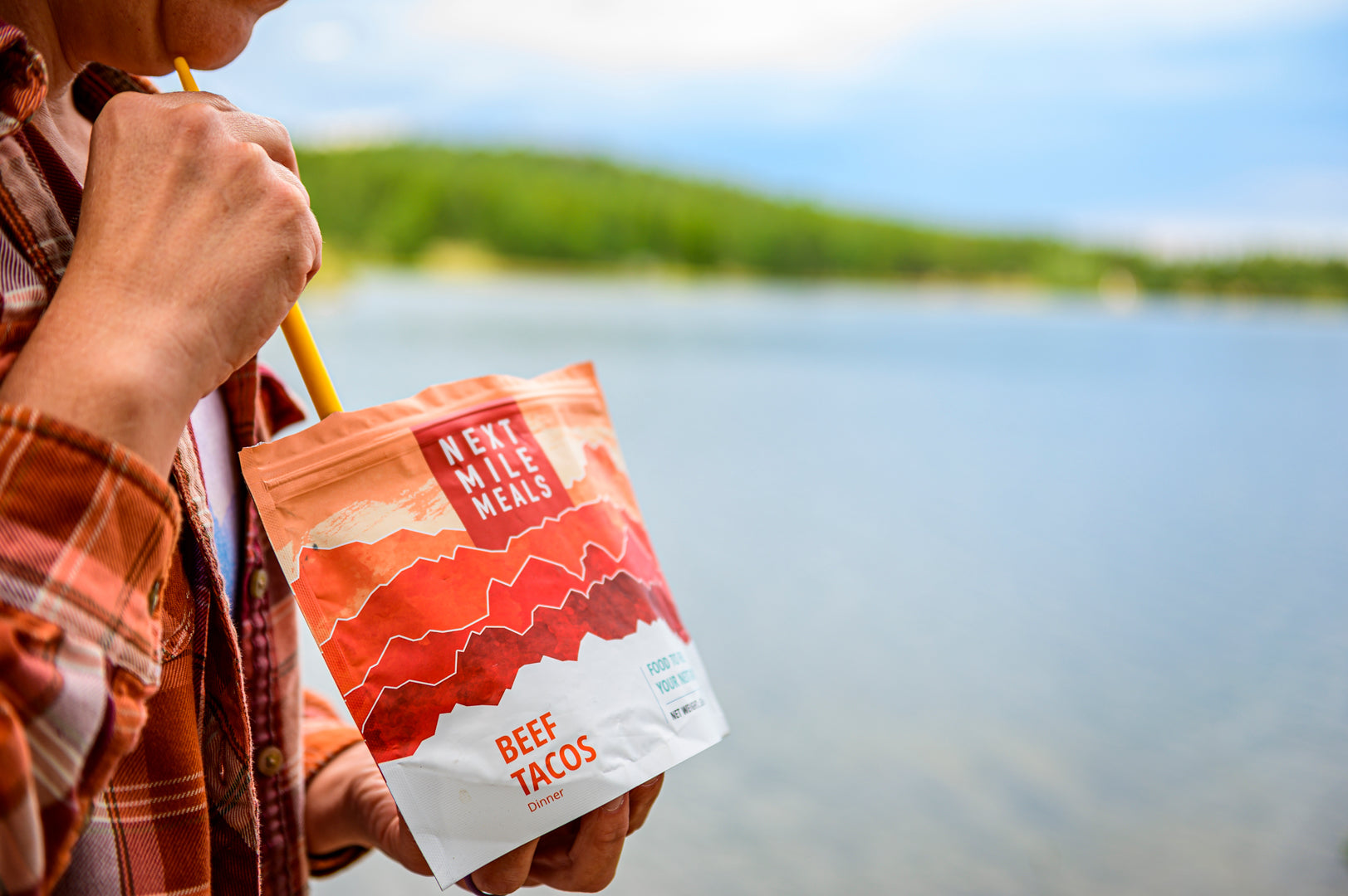 A backpacker with Next Mile Meals' Beef Tacos by the water