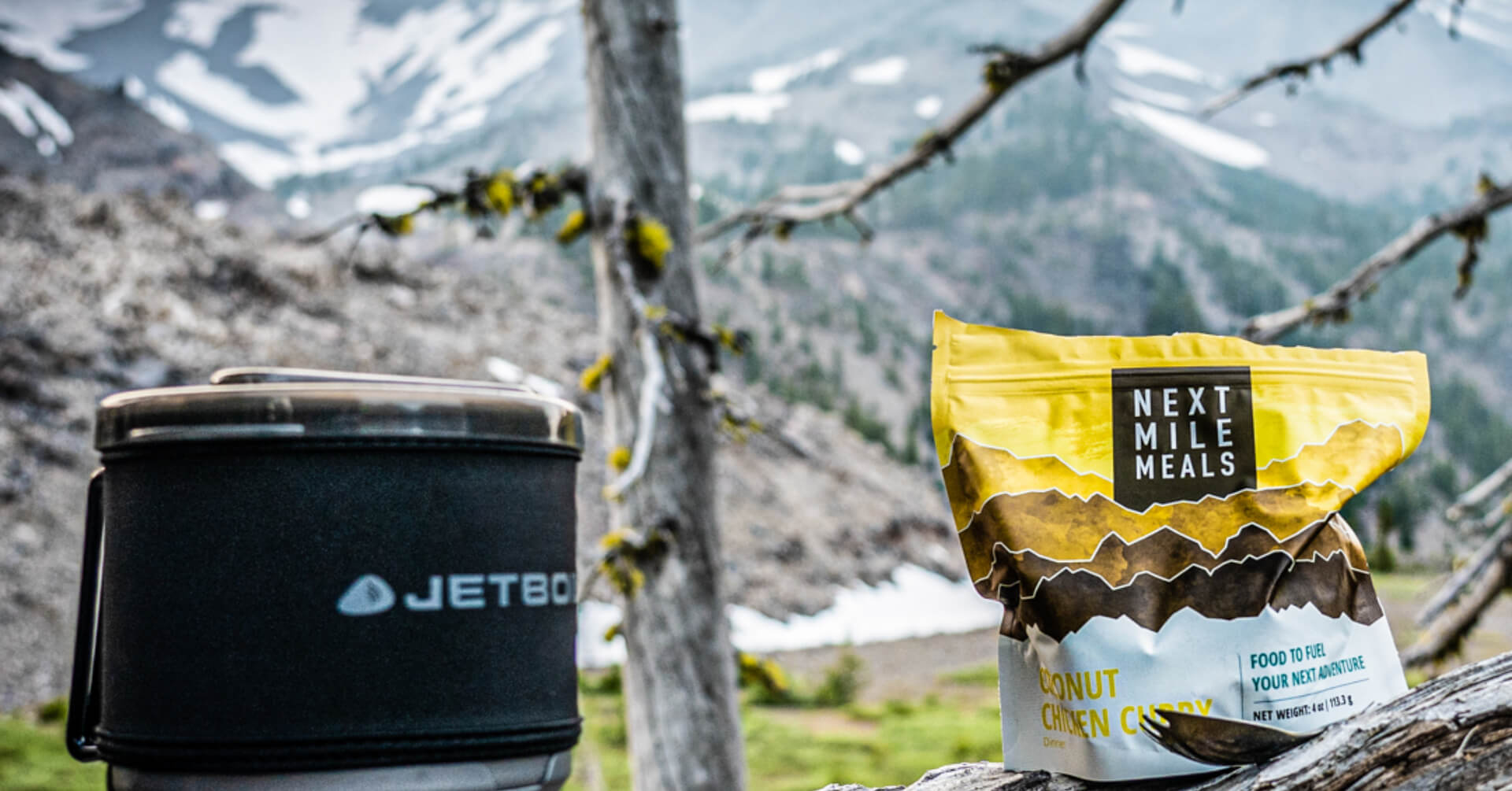 A Next Mile Meals Chicken Curry backpacking meal bag balanced on a tree branch.